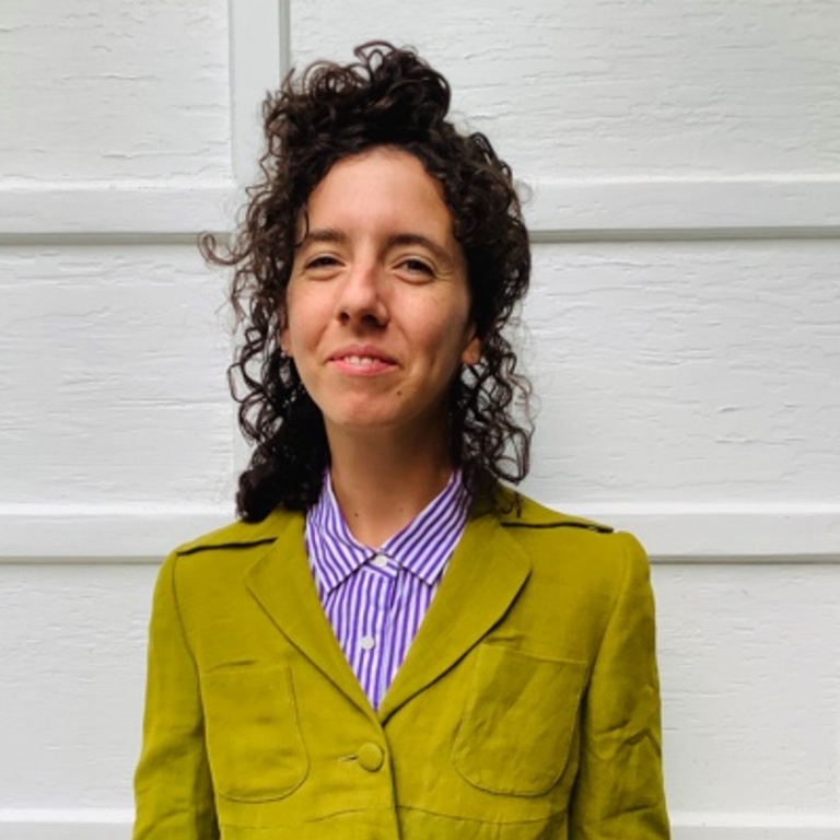 Woman with curly, dark hair wearing a chartreuse jacket