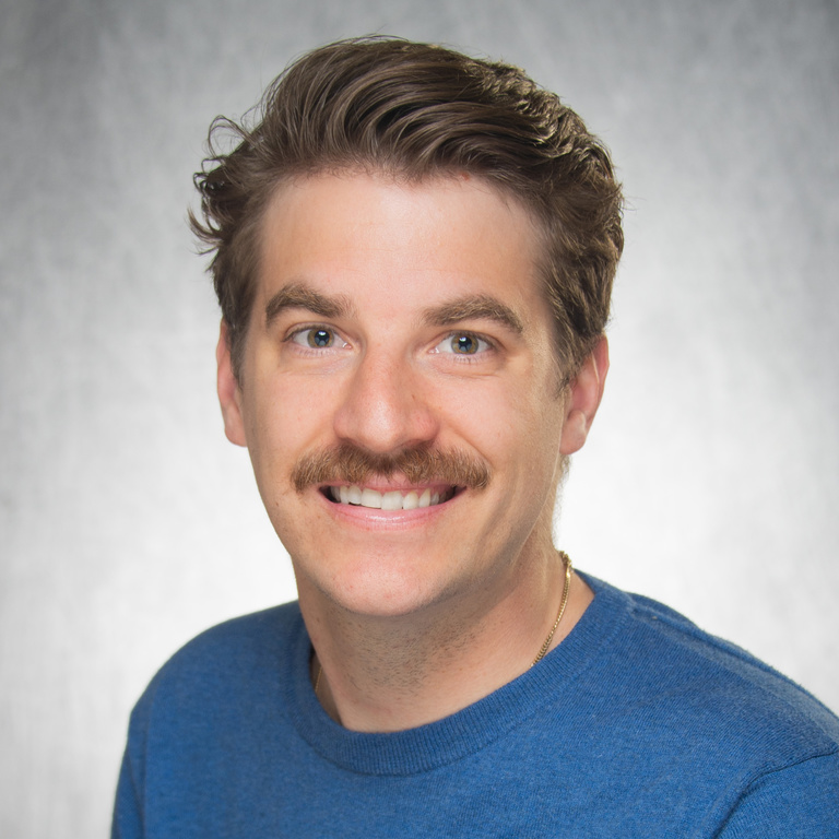 White man with moustache wears a bright blue crew-neck shirt